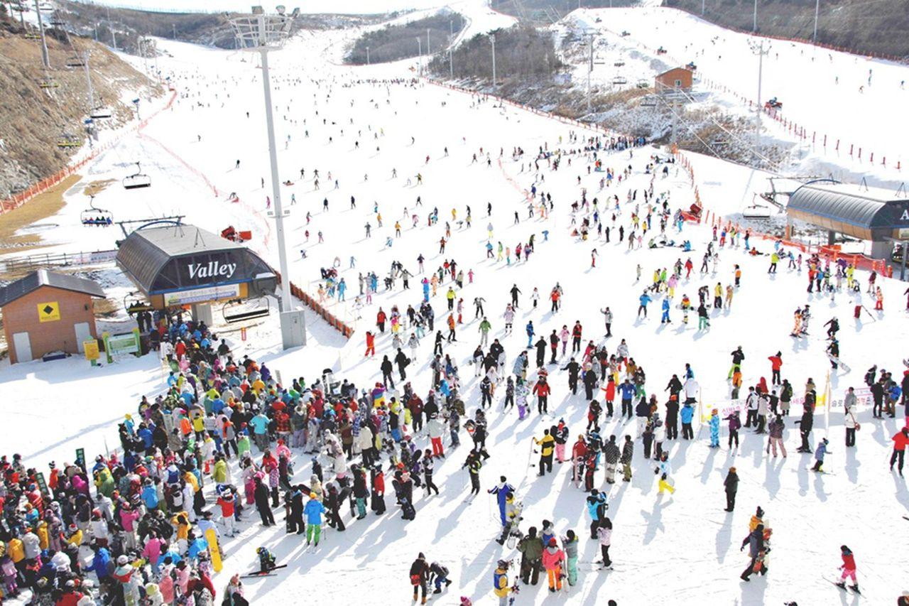 Elysian Gangchon Ski Resort, capturing a lively and bustling ski scene with skiers and snowboarders enjoying a vibrant winter day.