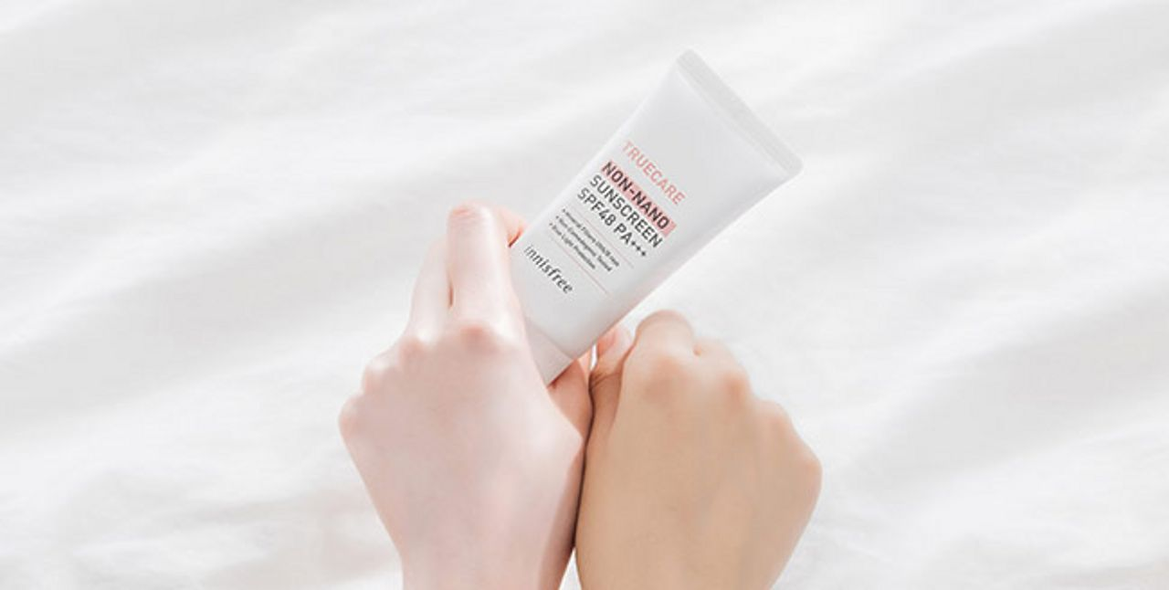 墊在白色牀單上的innisfree non-nano防曬霜和兩隻手的對比，展現防曬使用後的膚色變化。