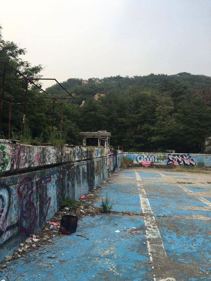 Detailed view of the decaying swimming pool and colorful graffiti on its walls at Seoul National University.