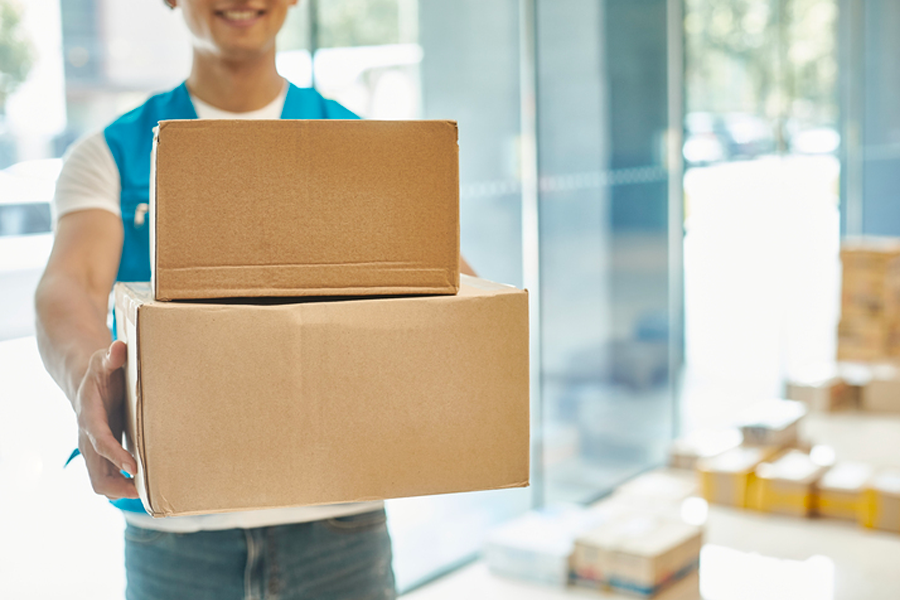 Person holding two brown cardboard packages, representing the concept of parcel delivery and shipments via Korea Post.