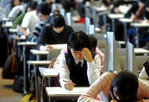 Students taking exams in a large hall, focusing on a test, representing educational pressure in Korea.
