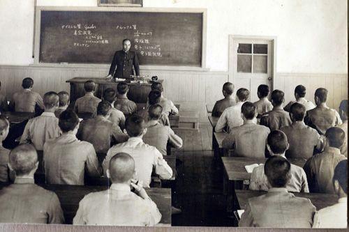 Vintage image of a classroom during the Japanese colonial period in Korea, showcasing students in uniform and a teacher.