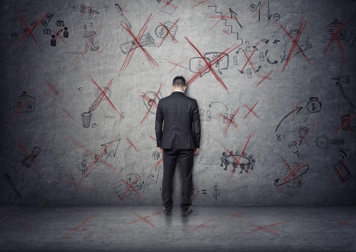 Businessperson facing chalkboard with rejected ideas, illustrating frustration and pressure in the workplace.