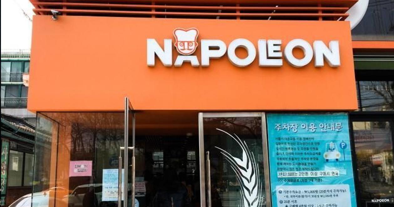 Cửa hàng bánh Napoleon Patisserie nổi bật với bảng hiệu màu cam đặc trưng tại Seoul, Hàn Quốc.