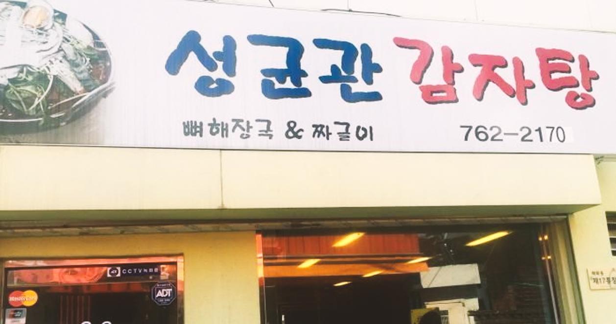 Bảng hiệu nhà hàng Sungkyunkwan Gamjatang, nổi bật với chữ '성균관 감자탕' trên nền trắng, nổi tiếng với món canh xương heo.