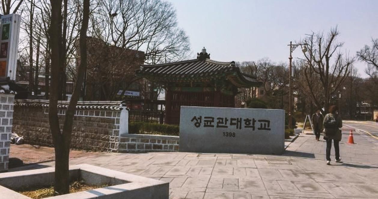 Cổng chính của Đại học Sungkyunkwan ở Hàn Quốc, nổi tiếng với dòng chữ '성균관대학교' và có một công trình truyền thống nhỏ phía sau.