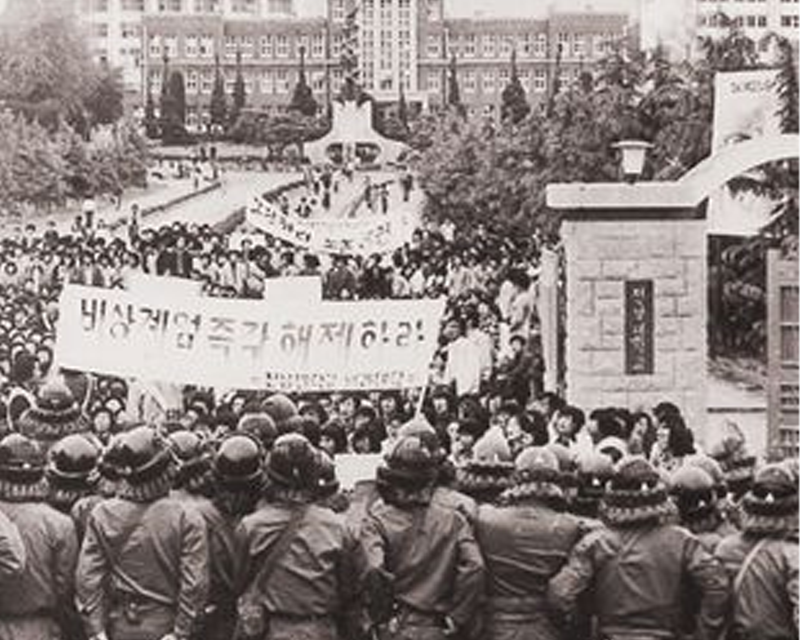 光州街頭的軍隊鎮暴，運送車輛旁多位全副武裝的士兵行進，當時的混亂局勢縮影。