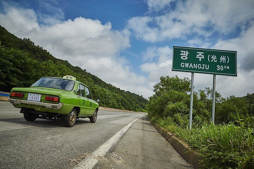 A green taxi on a road heading towards Gwangju, symbolic of the journey to document the Gwangju Uprising events