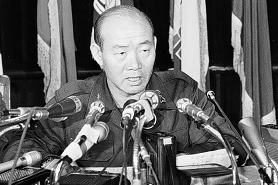 An individual speaking at a conference with multiple microphones, related to South Korean military or political events