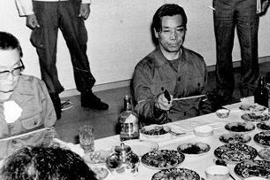 Black and white photo showing a group of people sitting at a table filled with dishes and drinks, notable event related to Korean history