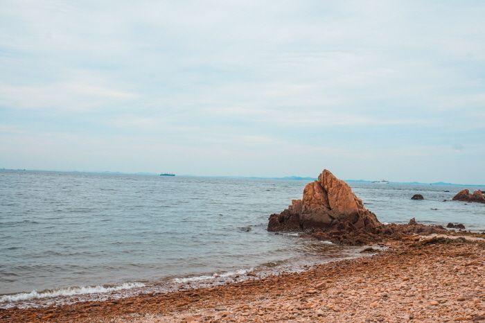 Rocky formation along the coast of Hanagae Beach with gentle waves.