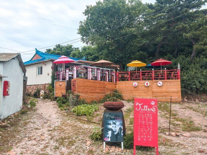A cozy café setup with colorful umbrellas overlooking the sea.