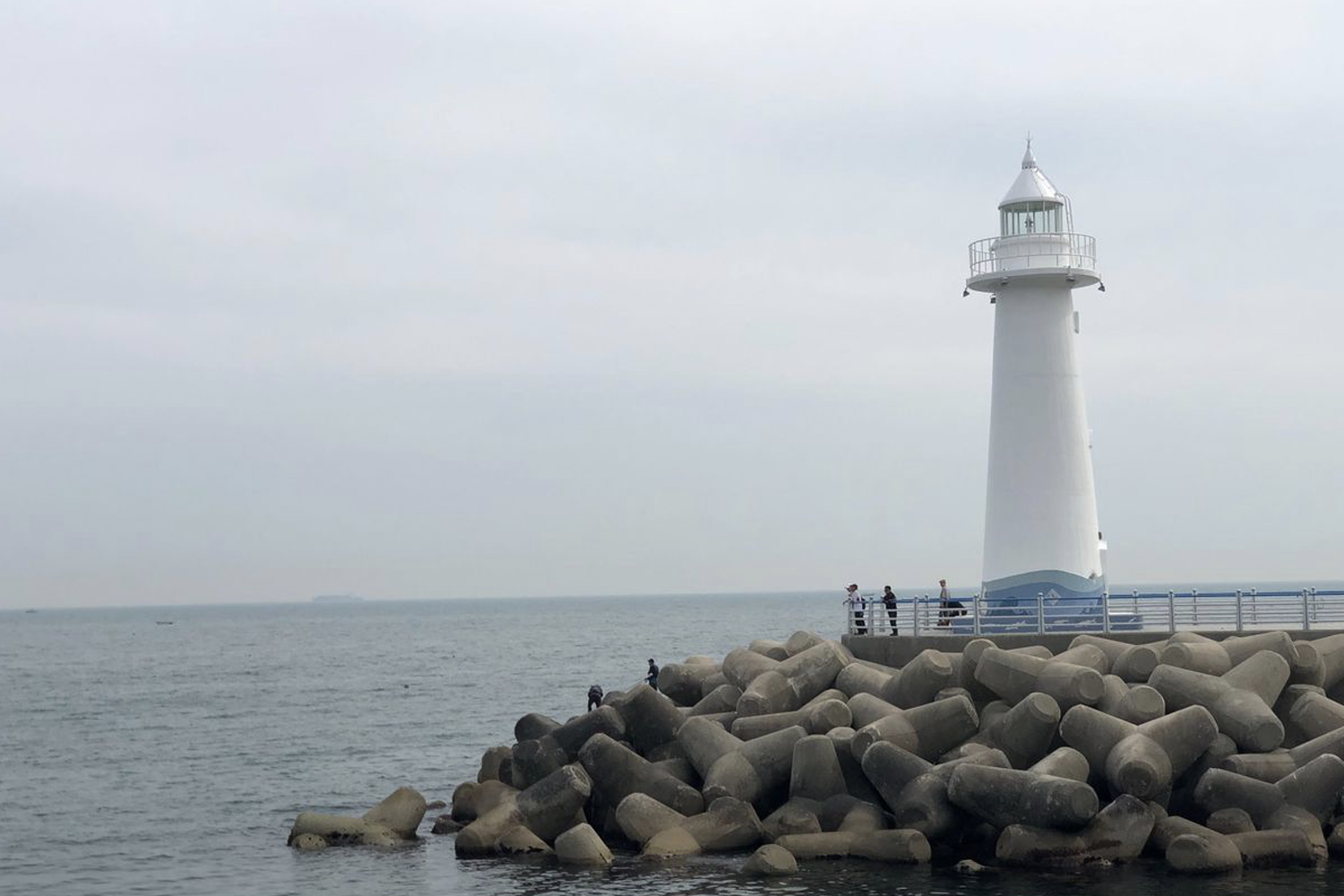 白色燈塔位於青沙浦的海岸線，遊客在燈塔周圍享受景觀。