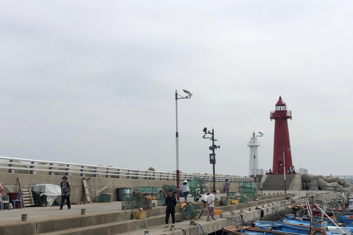 釜山青沙浦紅白燈塔，遊客在海邊漫步拍照。