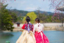 传统韩服体验的精彩画面，背景为古典建筑，展示韩国文化精髓。