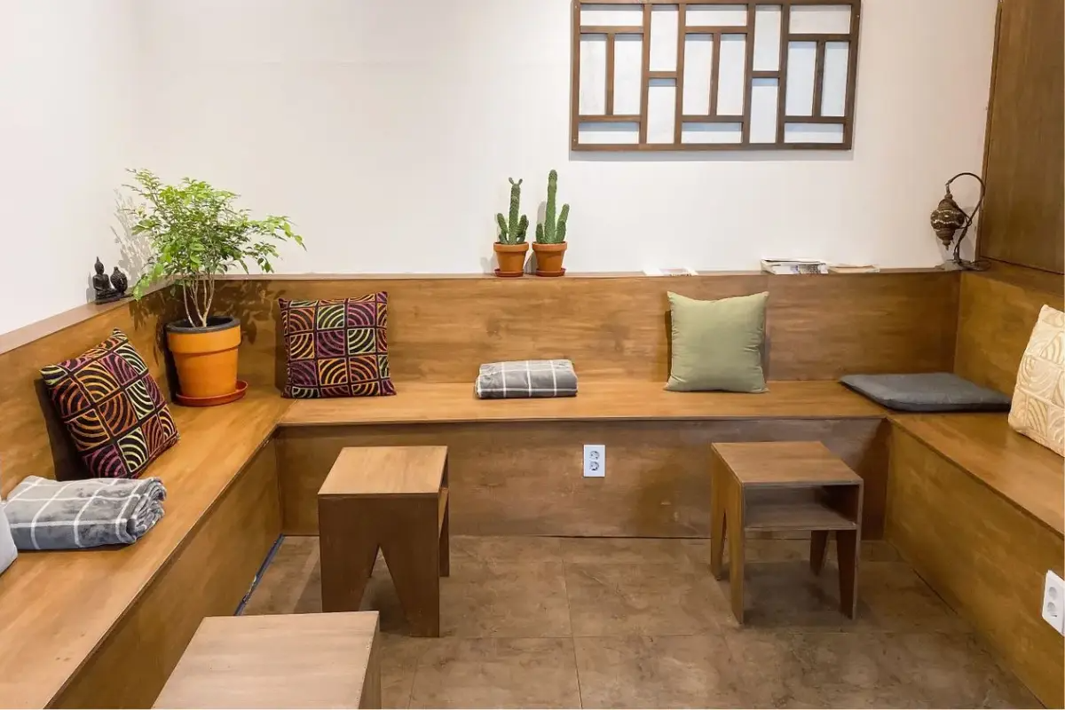 室內木製裝潢的休息區，搭配色彩鮮豔的靠墊和盆栽，展現韓屋般的舒適與温暖。