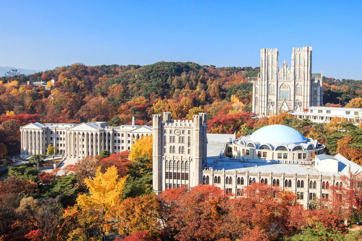 Kyunghee University campus in Korea surrounded by vibrant fall foliage showcasing red, orange, and yellow autumn leaves.