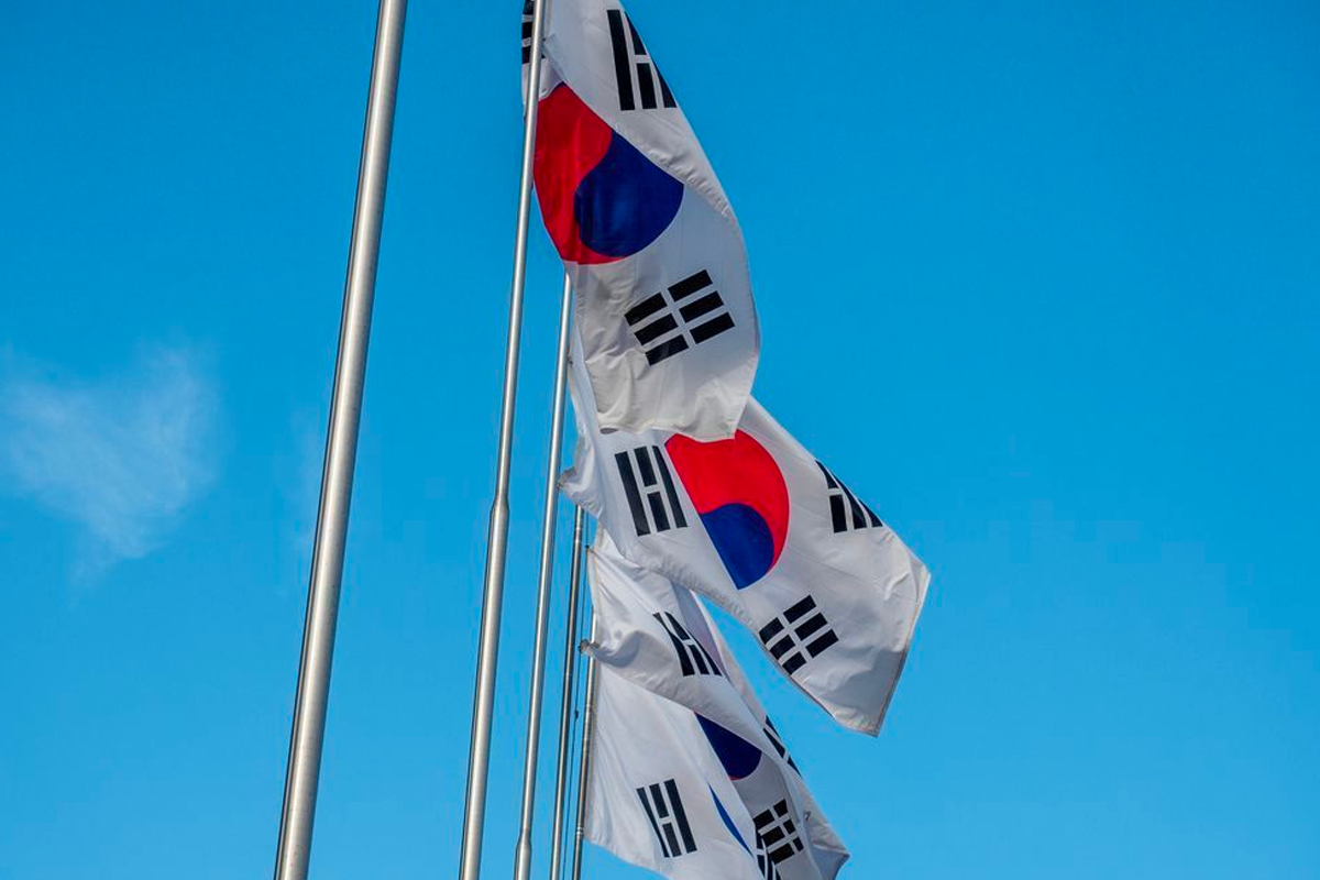Image of multiple Korean flags flying in the wind against a clear blue sky during the Korean national holiday, Gaecheonjeol