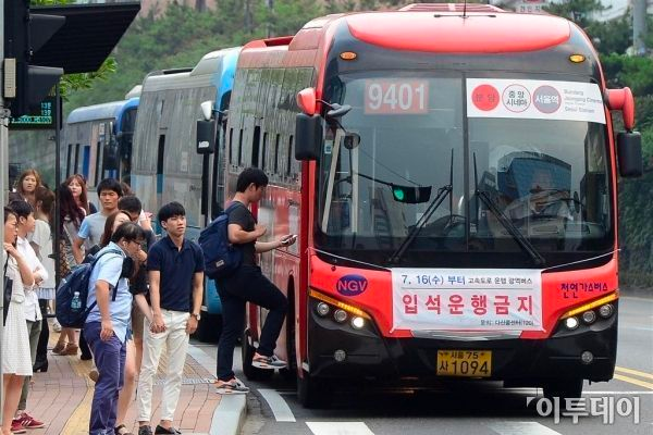 Red wide area bus in Seoul, number 9401, at a bus stop with passengers boarding.