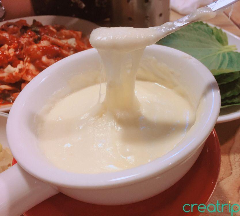 Cheese fondue stretching as a spoon is lifted, served at Fatty Octopus restaurant.