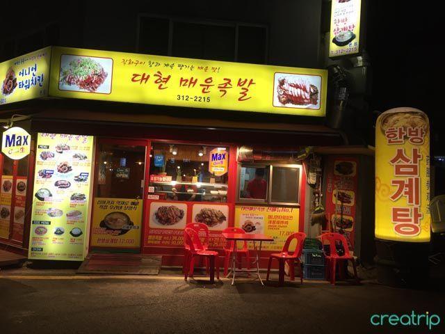 大岘辣猪脚店的招牌，红色和黄色的外观设计非常显眼，位于韩国首尔新村区。