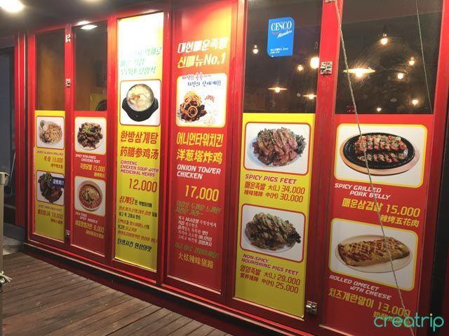 大岘辣猪脚店室内，展示墙上的菜单，推荐的特色菜品包括辣猪脚和洋葱塔炸鸡。