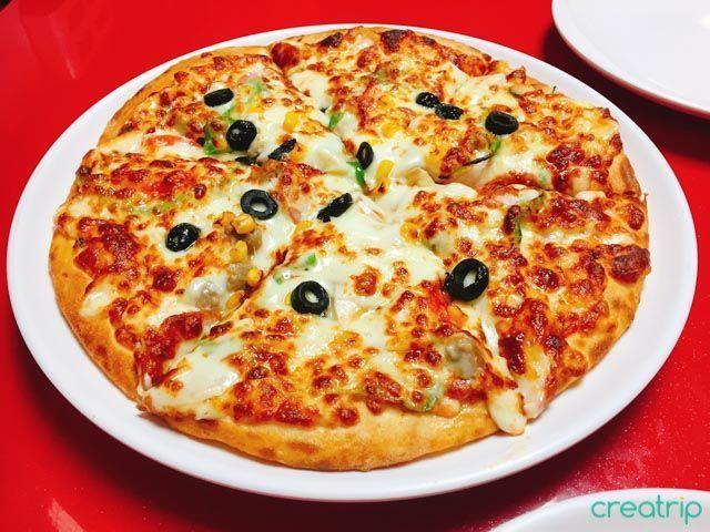 一份新鲜出炉的Pizza Rang组合什锦披萨，披萨表面覆盖丰富的馅料。