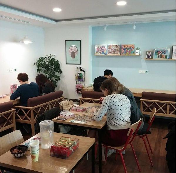 Inside a Korean puzzle cafe where patrons are engaged in puzzle activities, highlighting the diverse cafe themes in Korea.