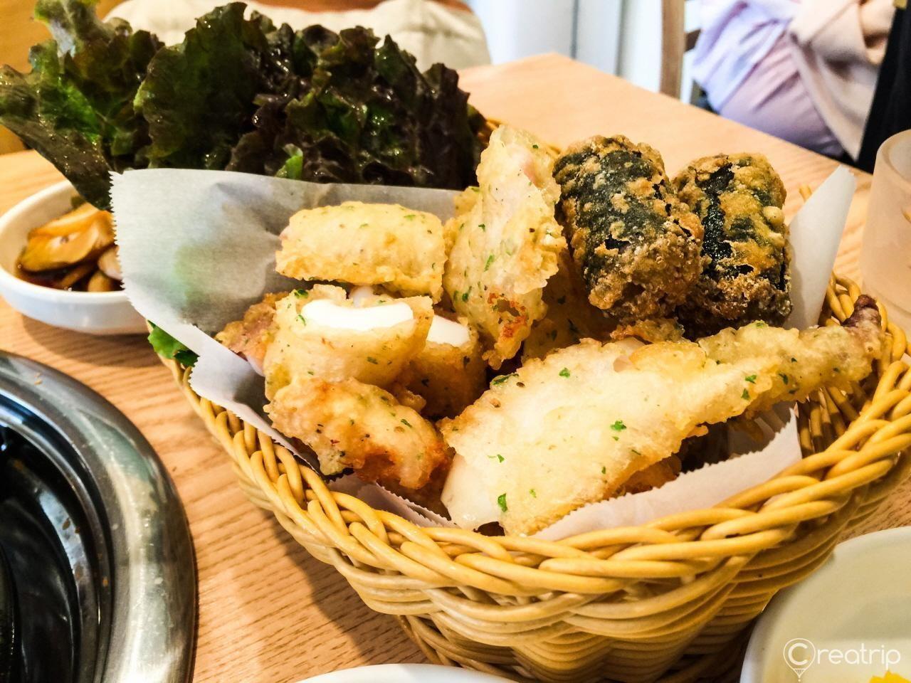 南岛面食馆，提供丰富的炸物，蘸料旁放着新鲜生菜。