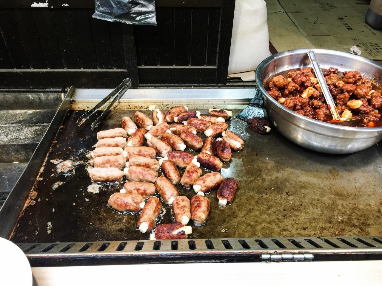 通仁市场摊位上显示不同的炒物和小吃，在韩国传统市场中体验食物的多样性。