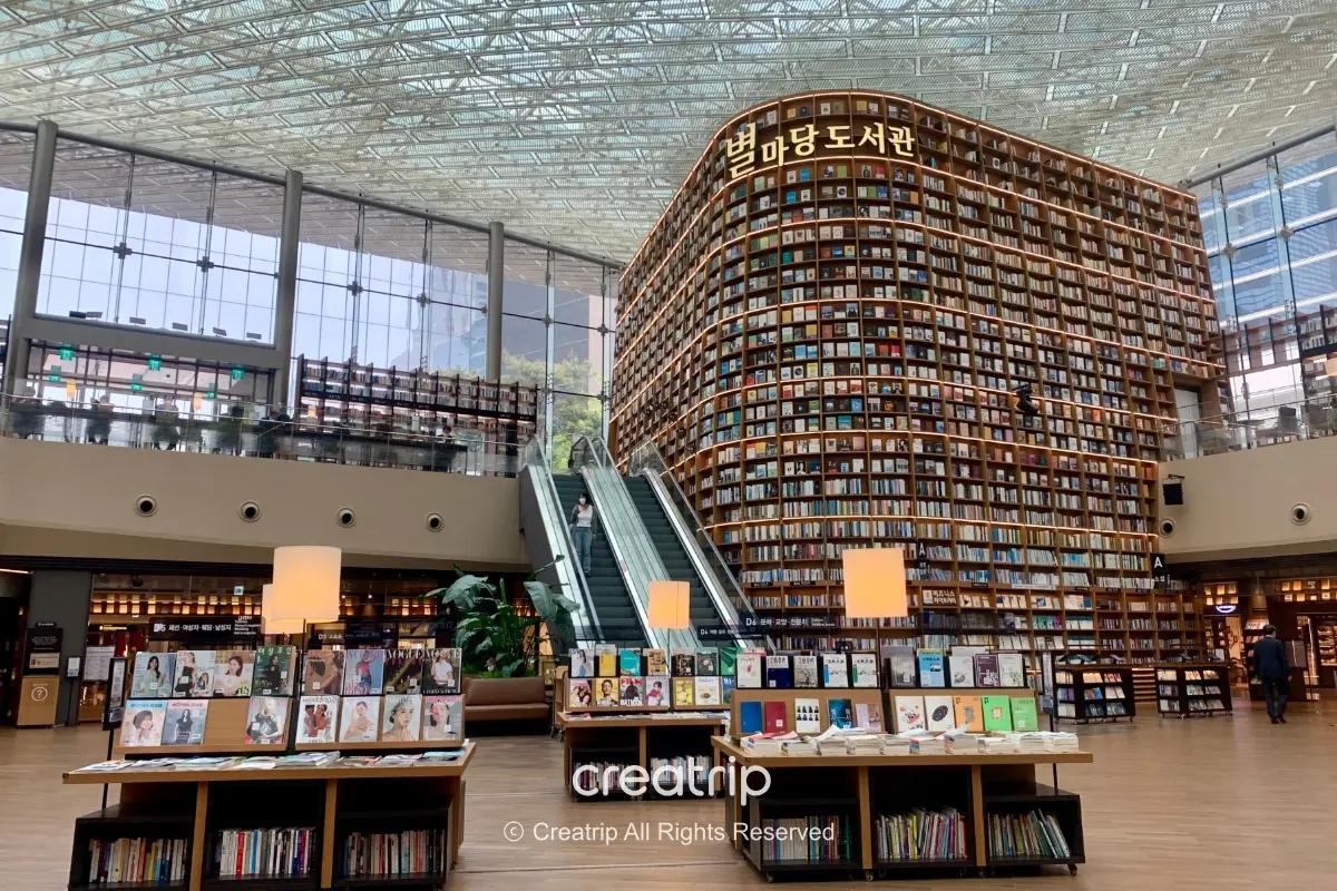 首爾COEX星空圖書館內景:巨大弧形書牆、中央手扶梯與展書桌,示範雨天或酷暑可安排的室內打卡與閱讀行程
