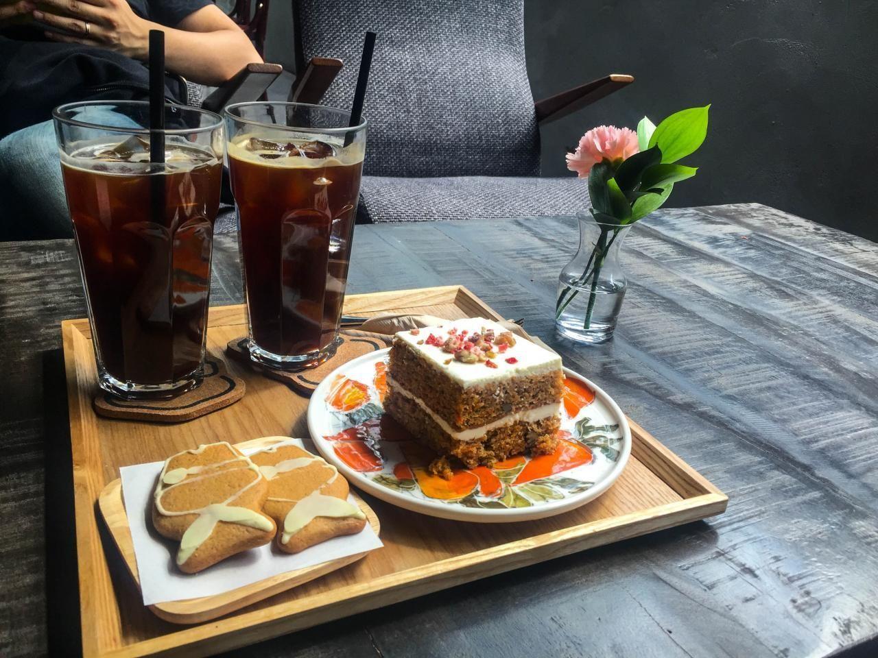 A cozy café setting in Seongsu-dong, featuring two glasses of iced coffee and a plate of cake and cookies on a wooden table.