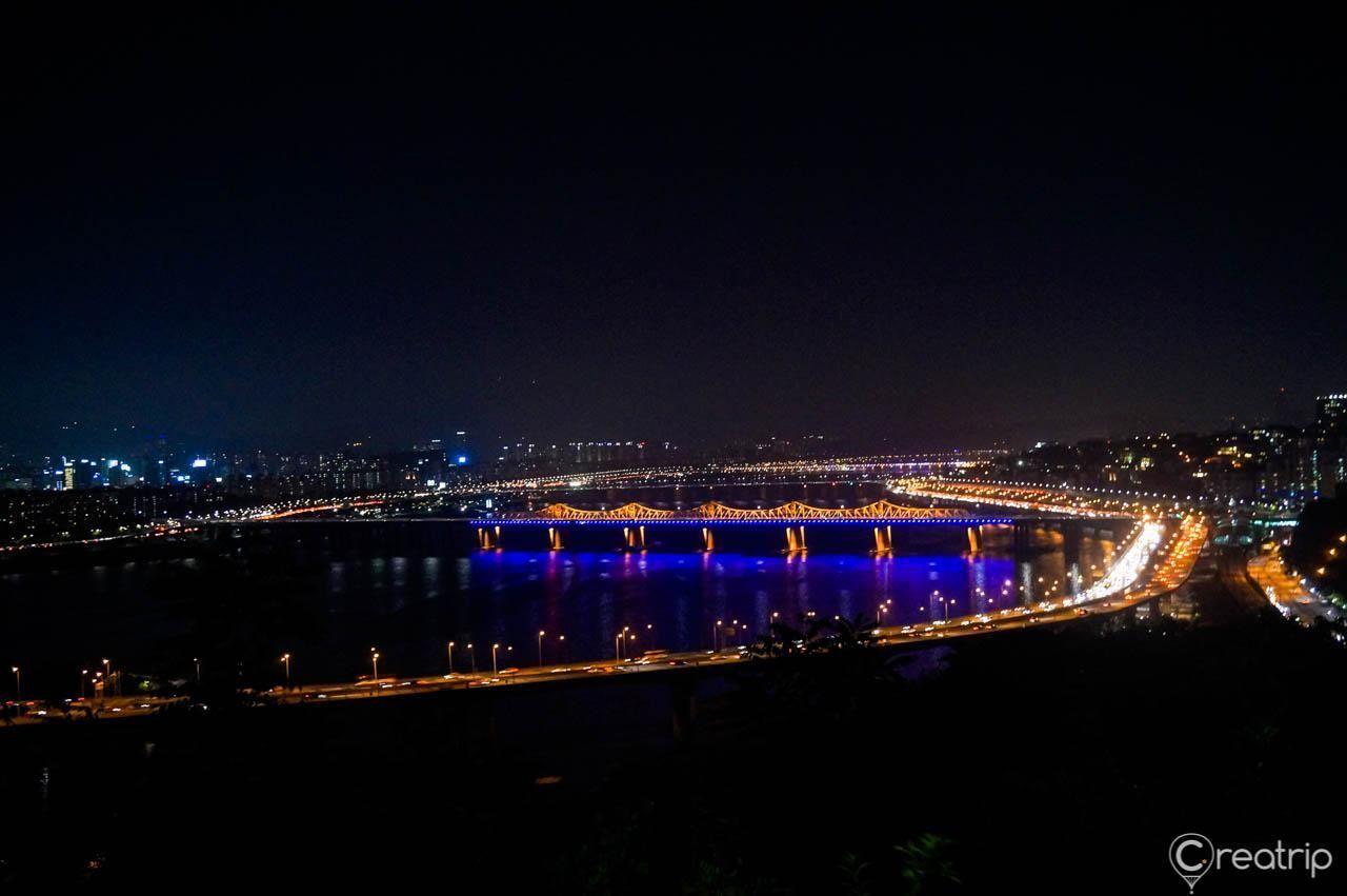 A stunning night view of the Han River from Ünpong Mountain, featuring illuminated bridges and city lights of Seoul.