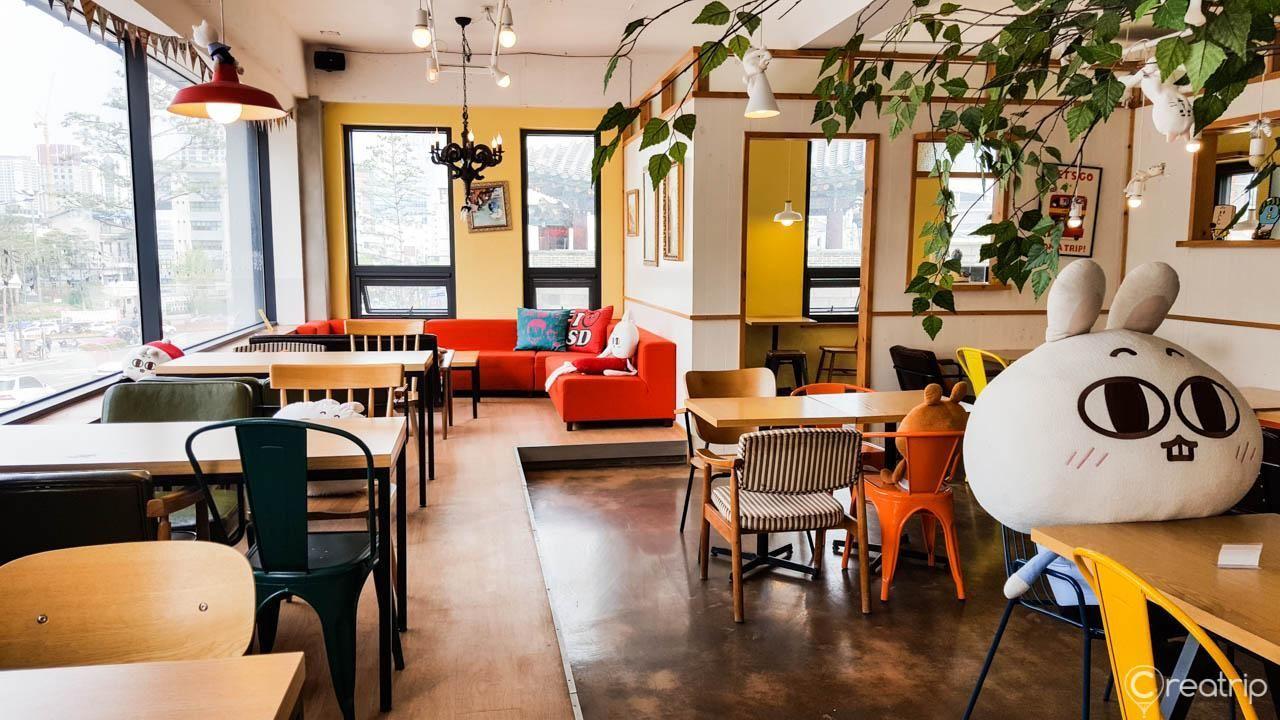 Interior of MAJOandSADY Cafe in Seoul, Korea, featuring themed decor with plush character dolls and colorful seating.