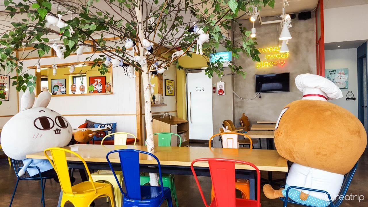 A cozy table setting with a rainbow cake roll and iced coffee at MAJOandSADY Cafe, a themed cafe in Seoul, Korea.