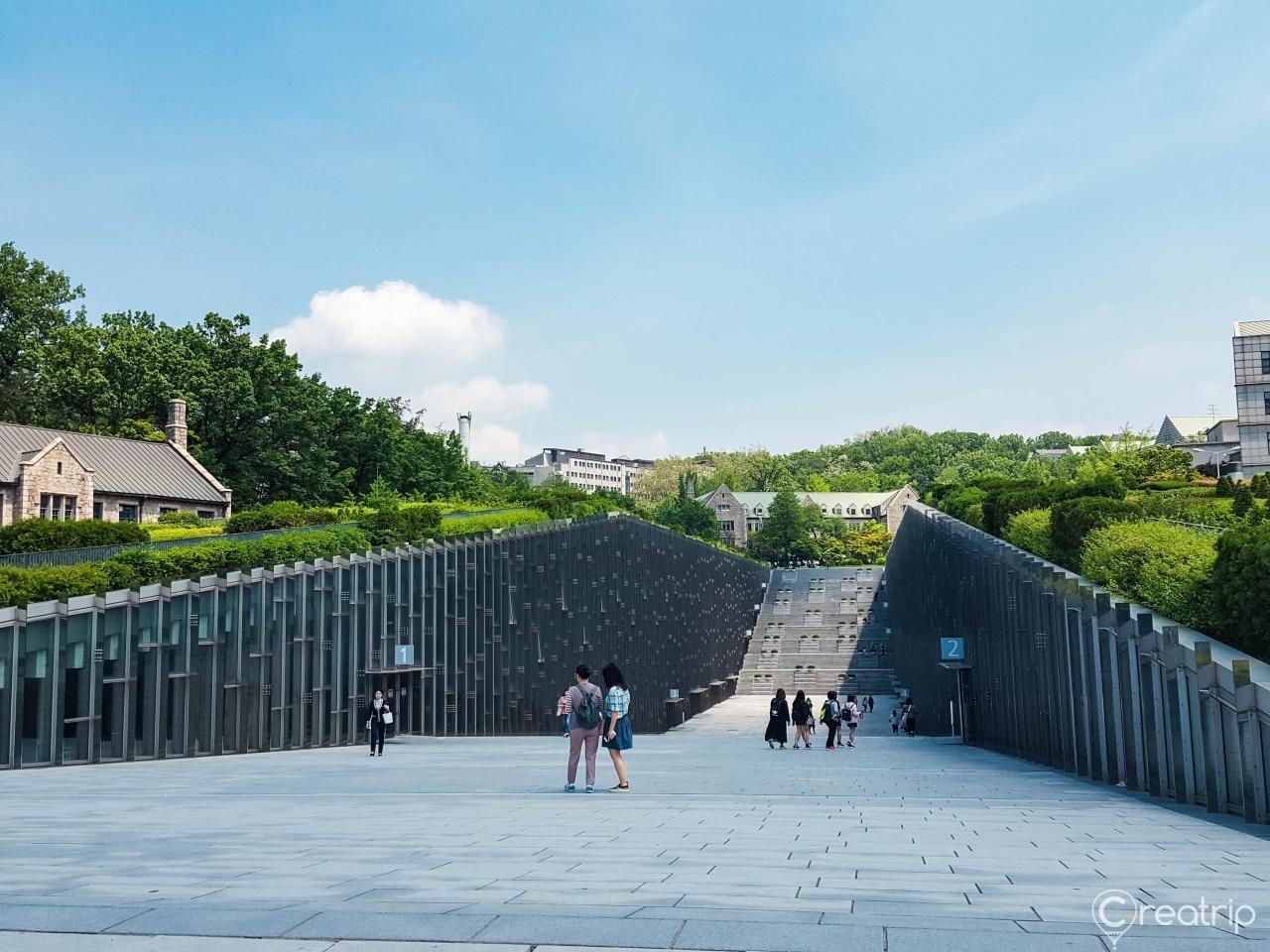 梨花女子大学校园，现代建筑设计与自然景色的融合，游客在宽敞的通道上观光。韩国首尔的著名学术与观光地点。