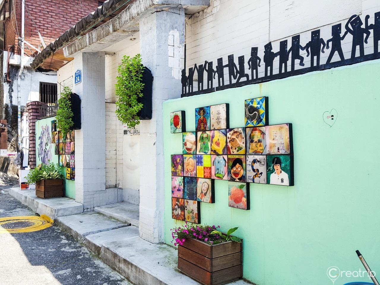 盐里洞的艺术墙面，墙上装饰着多彩的艺术画作和植物。首尔的盐里洞因其独特风格和活力壁画而受到游客欢迎。