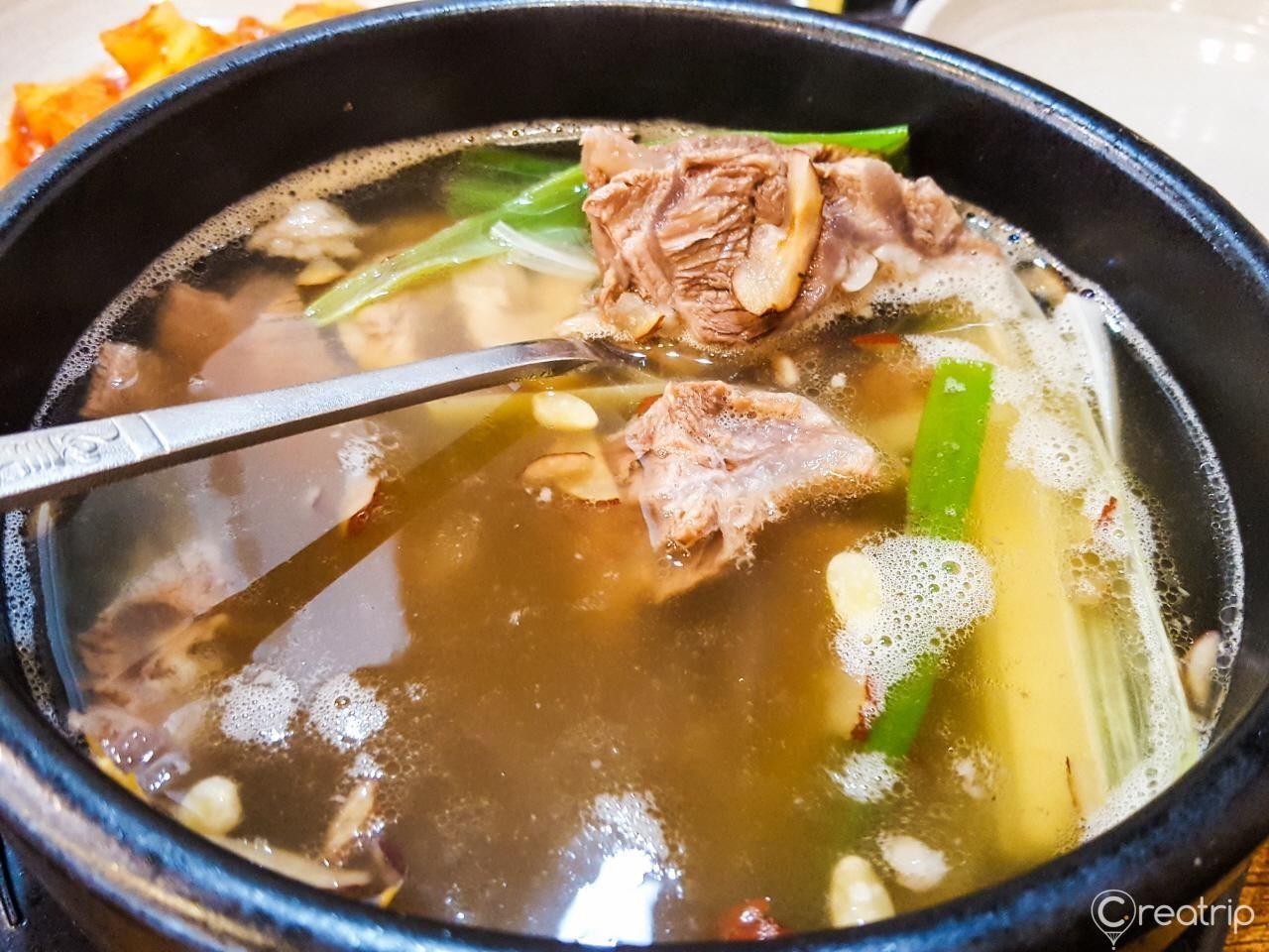 咸平面屋的韩式排骨汤，骨肉丰满，汤中撒着葱花，展现韩国传统美食的精致与丰富。