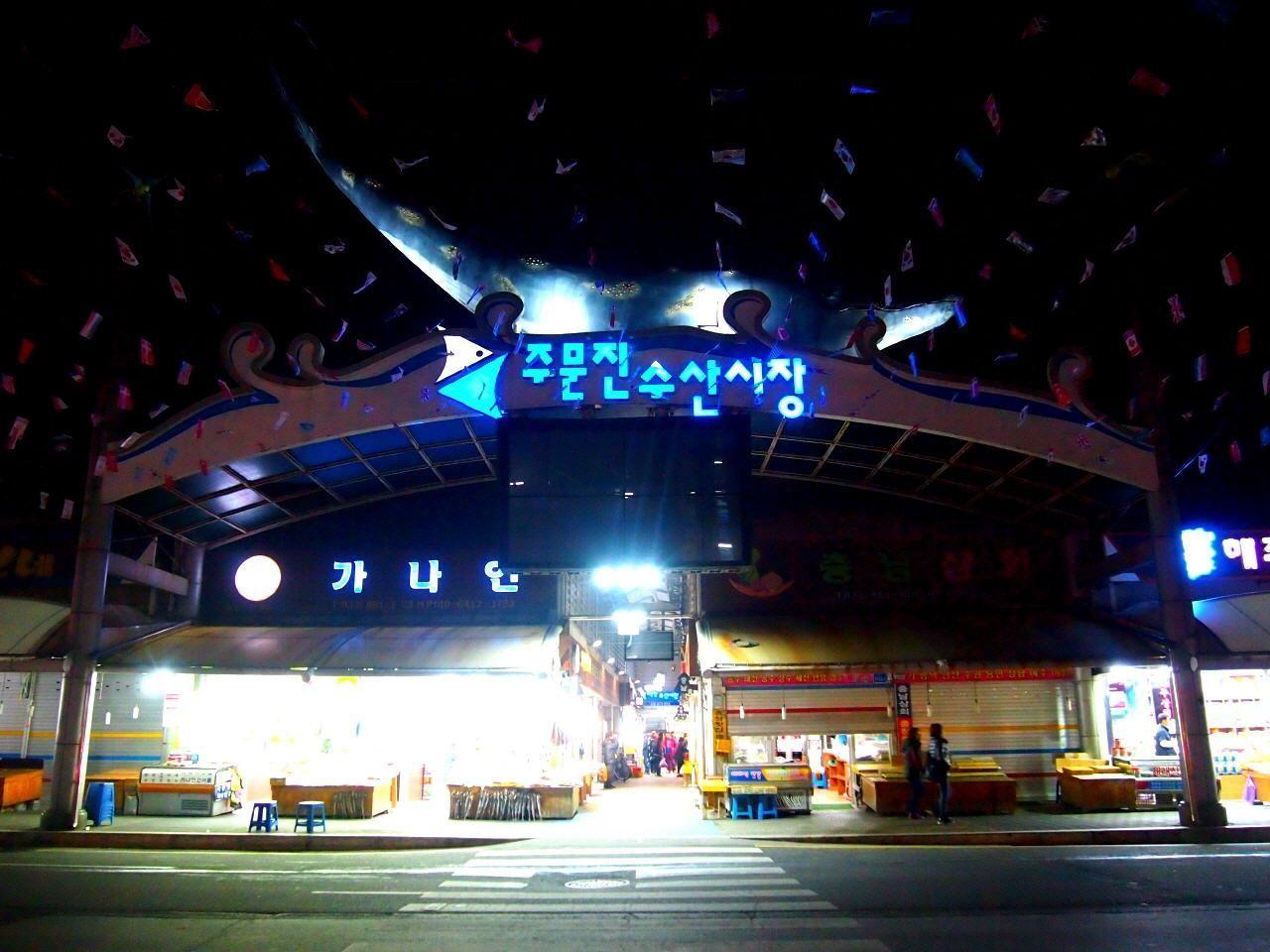 註文津水產市場的入口，夜晚散發著明亮的招牌燈光。