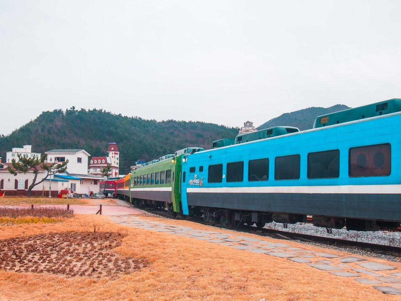 正東津站的火車在海邊停靠，背景為山林景色。