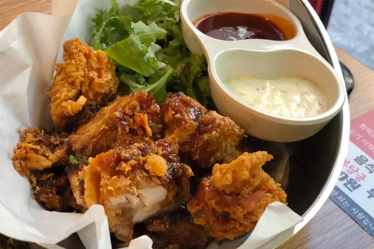 韓国のフライドチキン、カリカリに揚がったジューシーなチキンとともにサラダとディップソースがセットになった一皿。