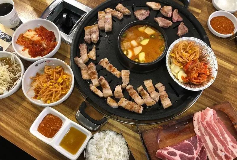 韓国料理店で提供される焼肉セット。中央にテンジャンチゲ、周りにキムチやサラダが並べられたテーブルの一部です。