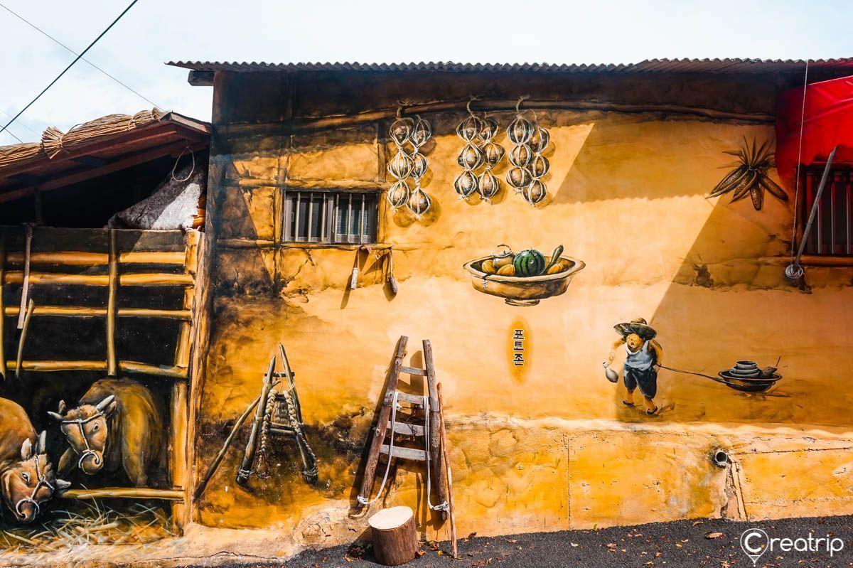 대구 마비정 벽화마을의 벽화로 빨간색 도장을 가진 전통적인 마을의 일상 모습이 그려져 있는 이미지.