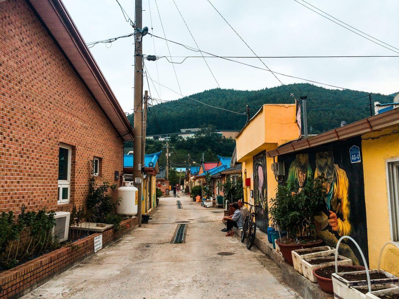 상장 벽화마을 내의 아담하고 한적한 거리 이미지. 벽에 그려진 탄광 벽화와 정돈된 거리 풍경이 조화를 이룹니다.