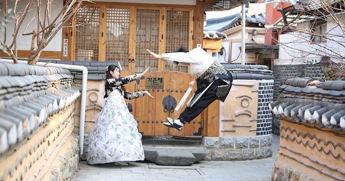Visitors in traditional Hanbok posing in Jeonju Hanok Village, Korea, showcasing cultural heritage and fun travel experience.