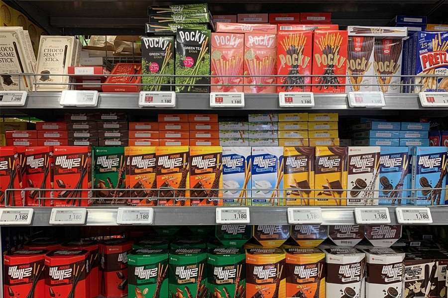 一家便利店内陈列着各种口味的Pepero和Pocky，它们的价格显示在标签上，标示出日期是11月11日Pepero Day。