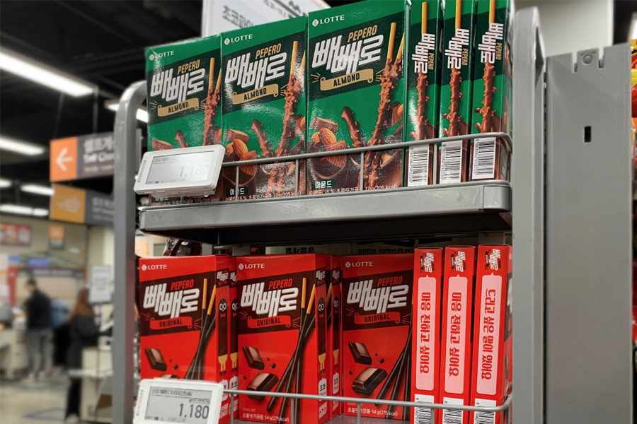 一架满是各种口味的Pepero巧克力棒的货架，展示了经典原味和杏仁口味的包装。