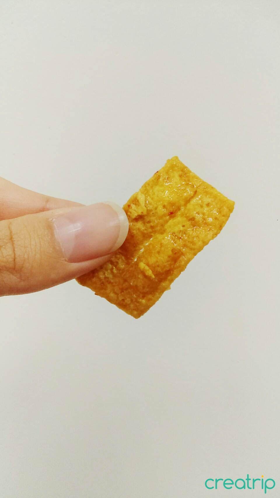 Hand holding a rectangular garlic corn chip from CU Korean snack packaging