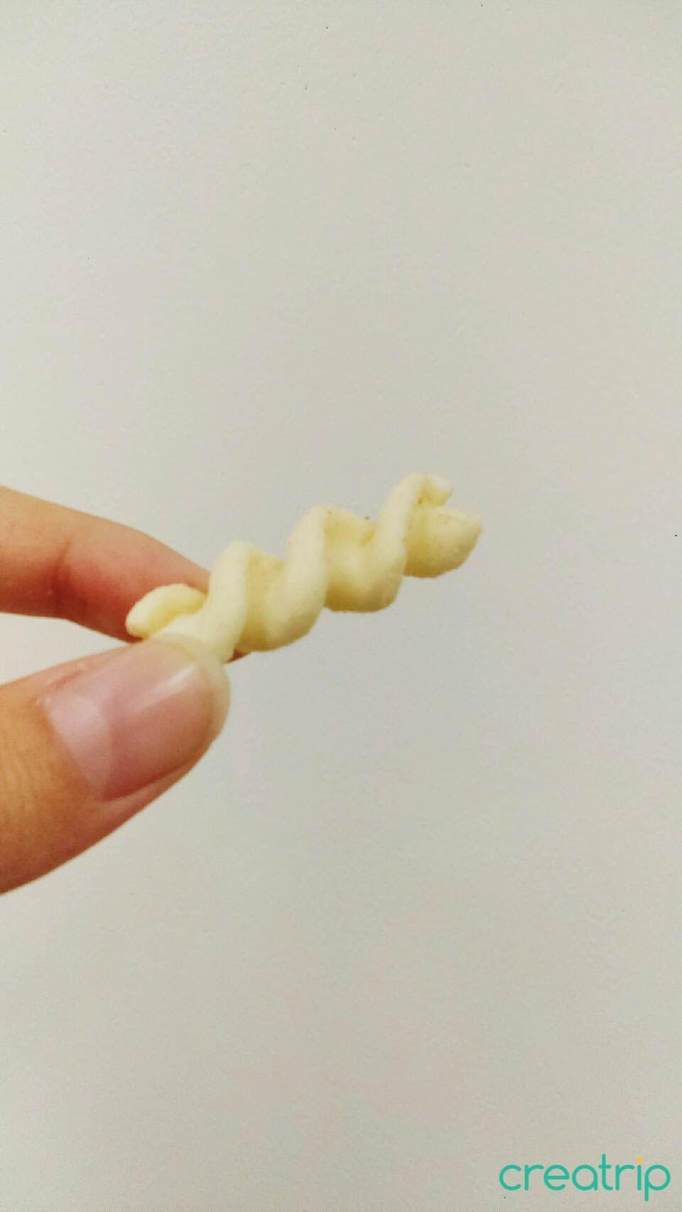 Hand holding a spiral garlic pasta snack from CU Korean convenience store