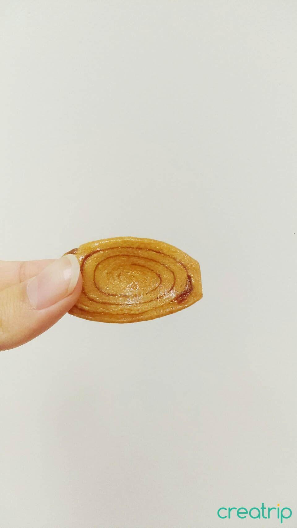 Hand holding a single sweet potato biscuit from CU convenience store resembling Taiwanese pig ear biscuits